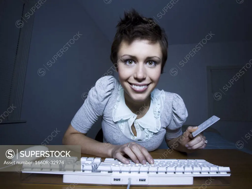 Woman sitting at keyboard with credit card
