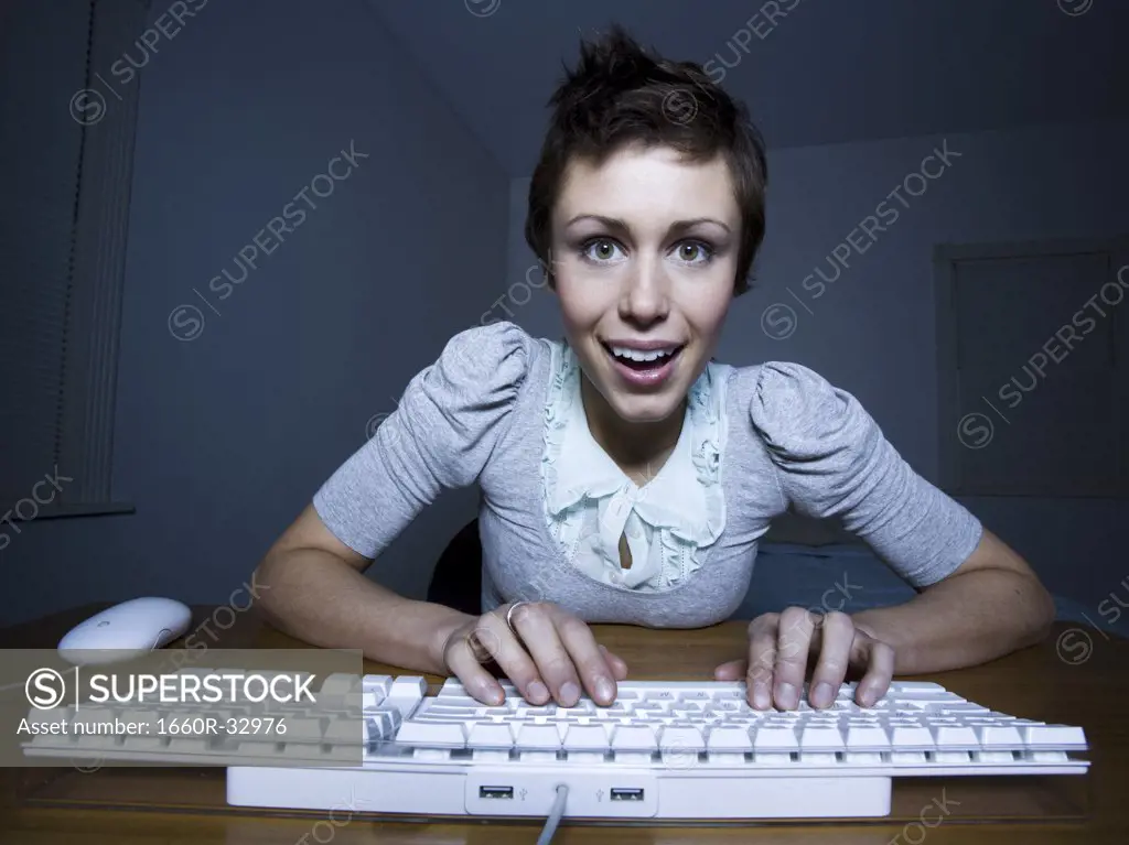 Woman sitting at keyboard typing and smiling
