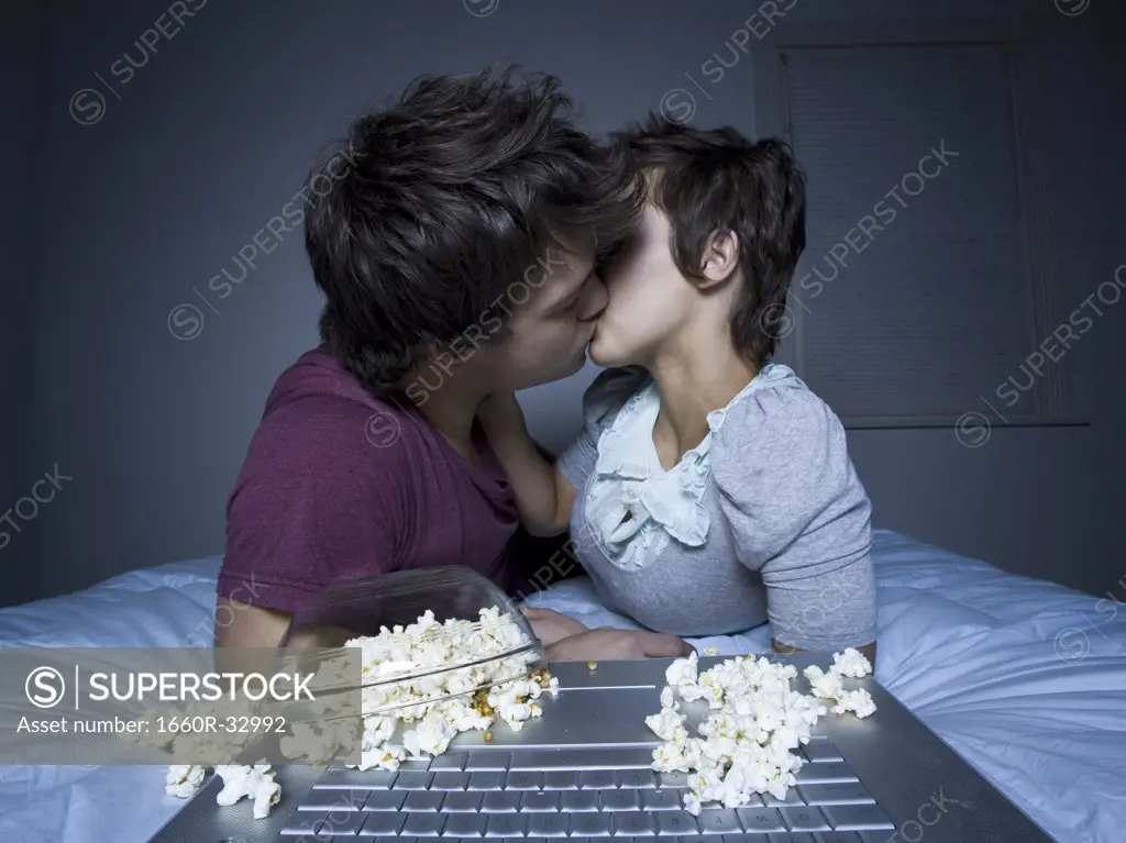 Couple kissing with upside down bowl of popcorn