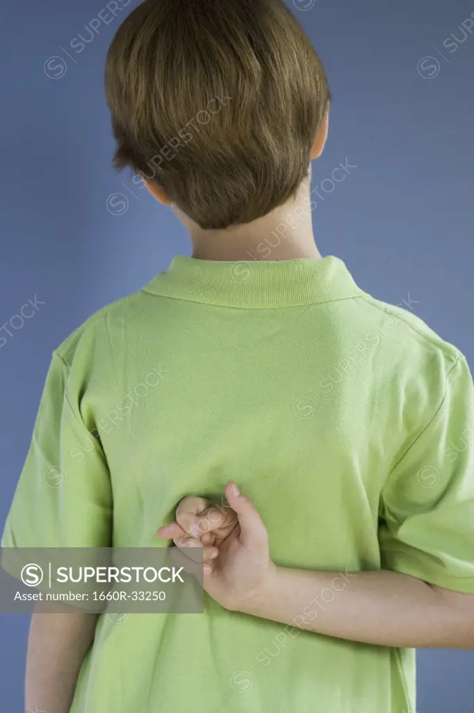 Rear view of boy with fingers crossed behind back