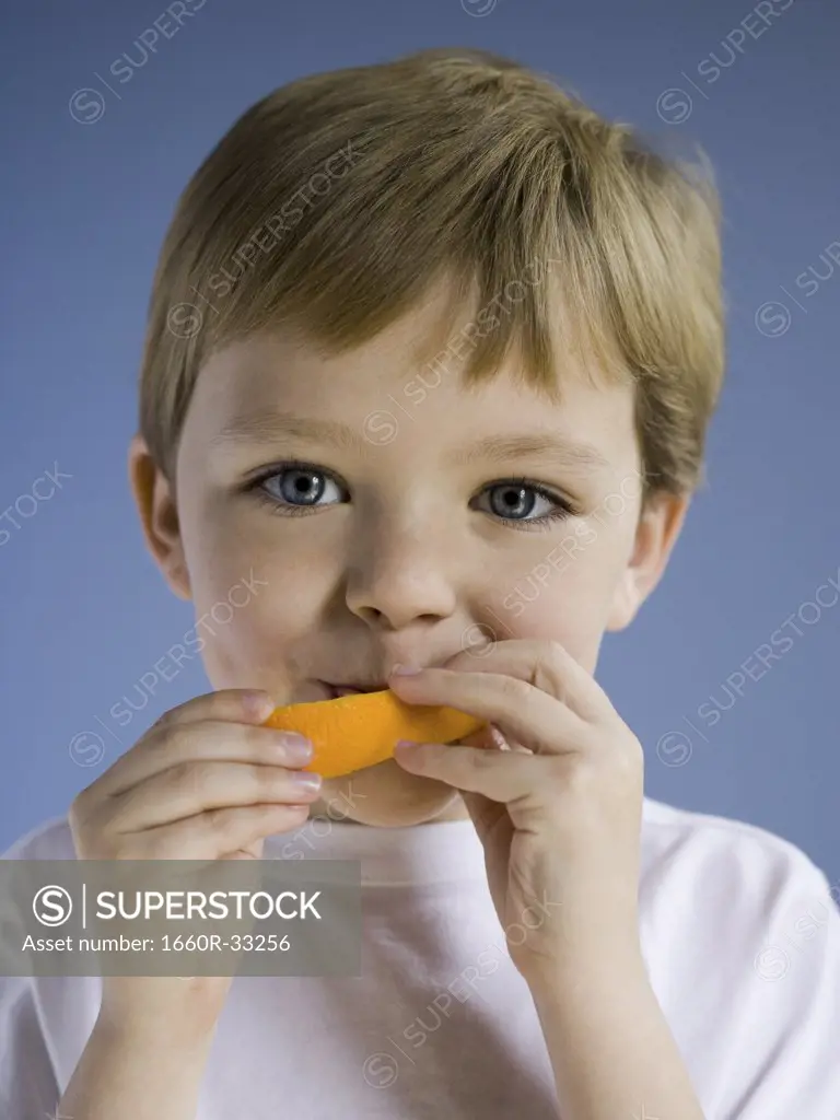 Closeup of boy eating orange wedge