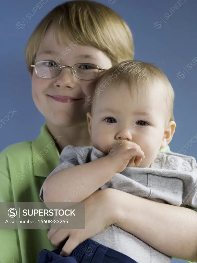 Boy with eyeglasses holding baby with eyes covered