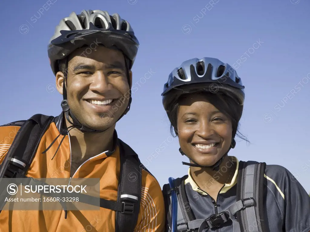 Man and woman with bicycles and helmets outdoors smiling