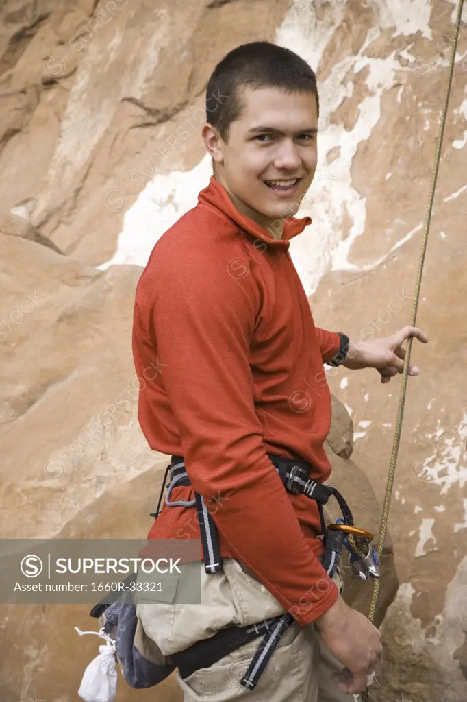 Man outdoors with climbing ropes and harness