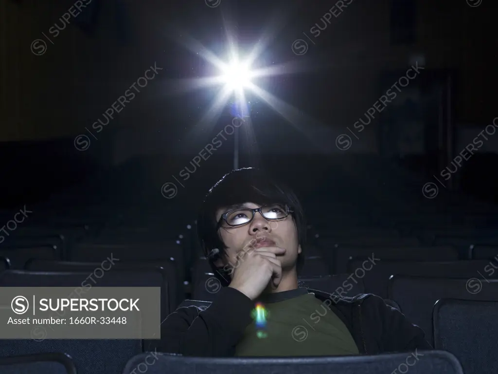 Man with eyeglasses watching film at movie theater