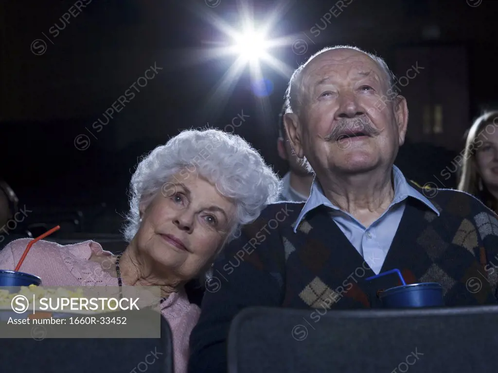 Man and woman watching film at movie theater smiling