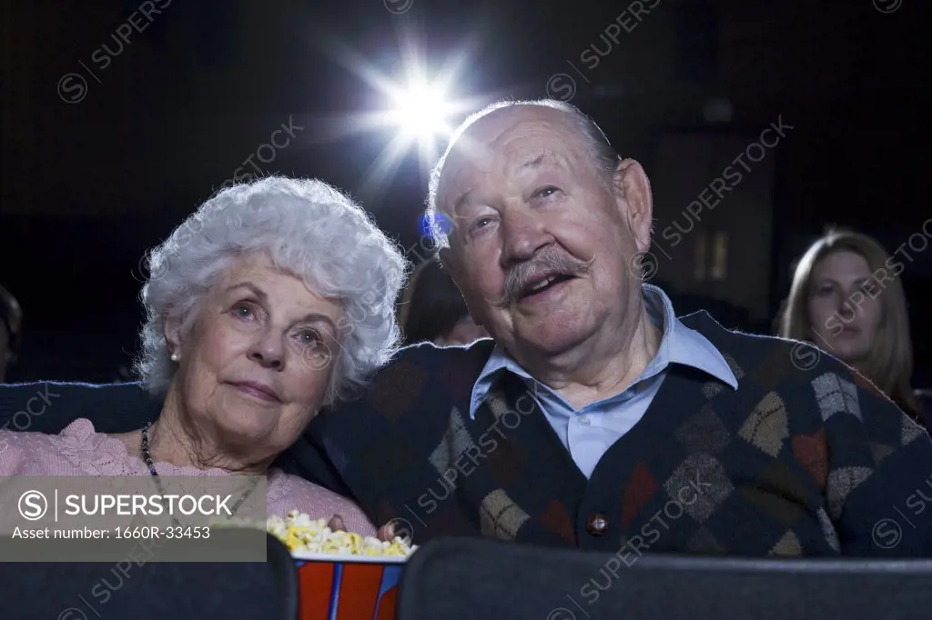 Man and woman watching film at movie theater smiling