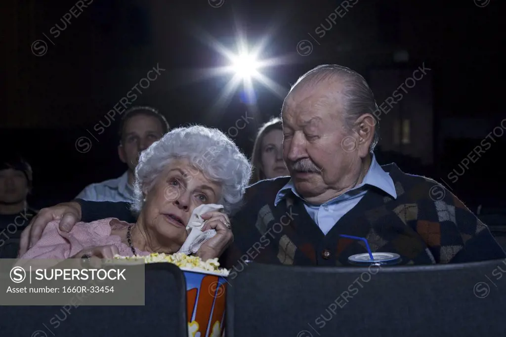 Man and woman watching movie in theater crying with popcorn