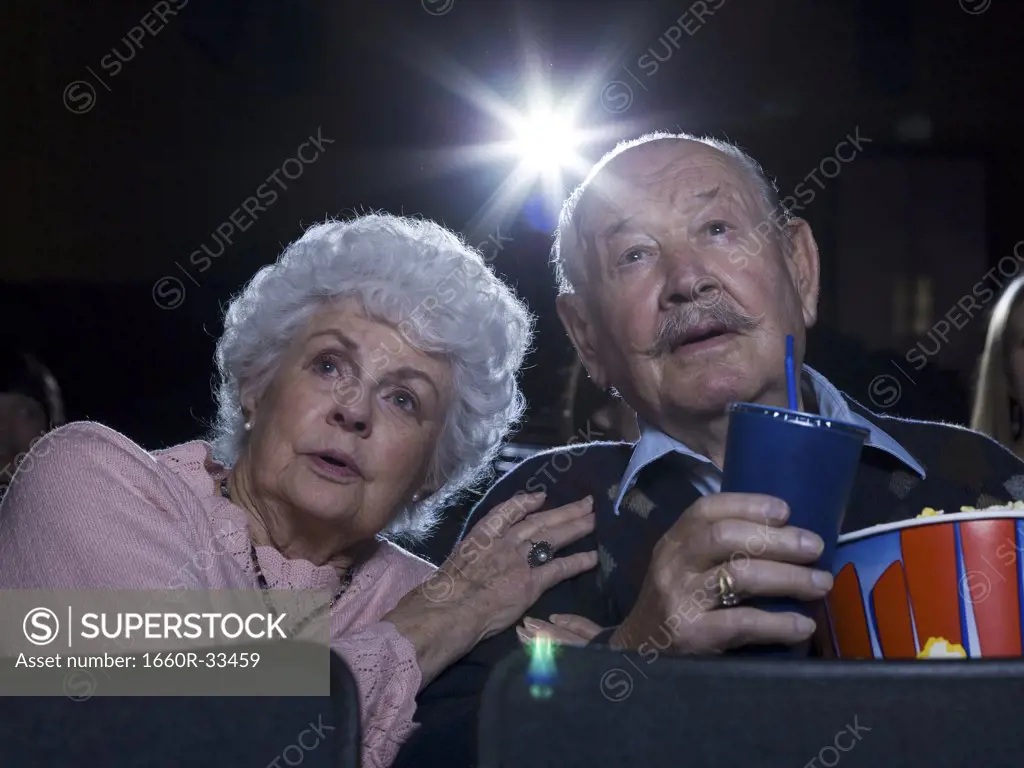 Man and woman watching film at movie theatre frightened