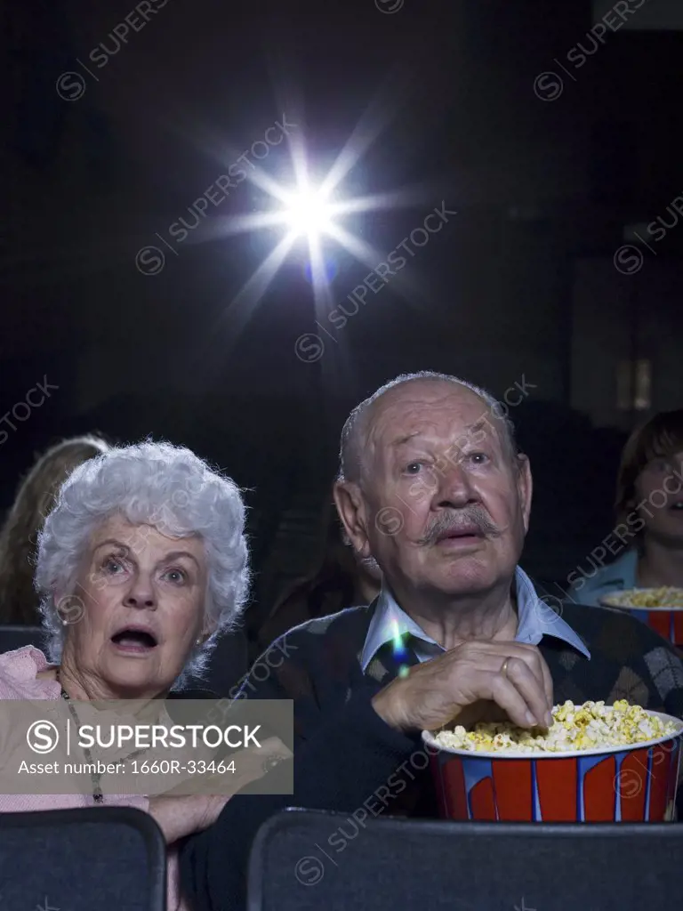 Man and woman watching film at movie theatre frightened