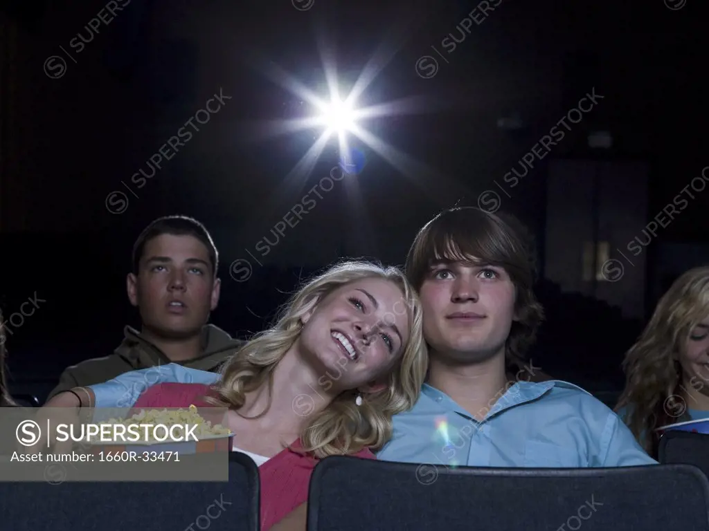 Boy and girl watching film at movie theater smiling