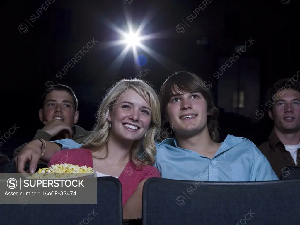 Boy and girl watching film at movie theater smiling