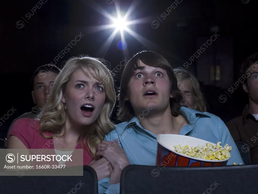 Boy and girl with popcorn frightened at movie theater