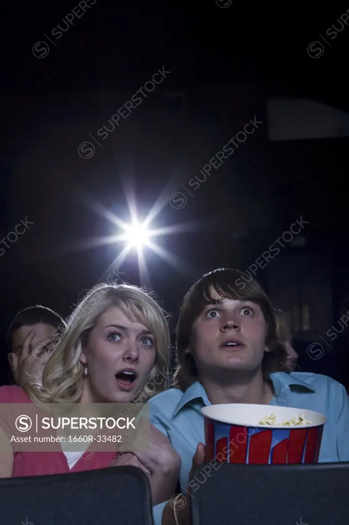 Boy and girl with popcorn frightened at movie theater