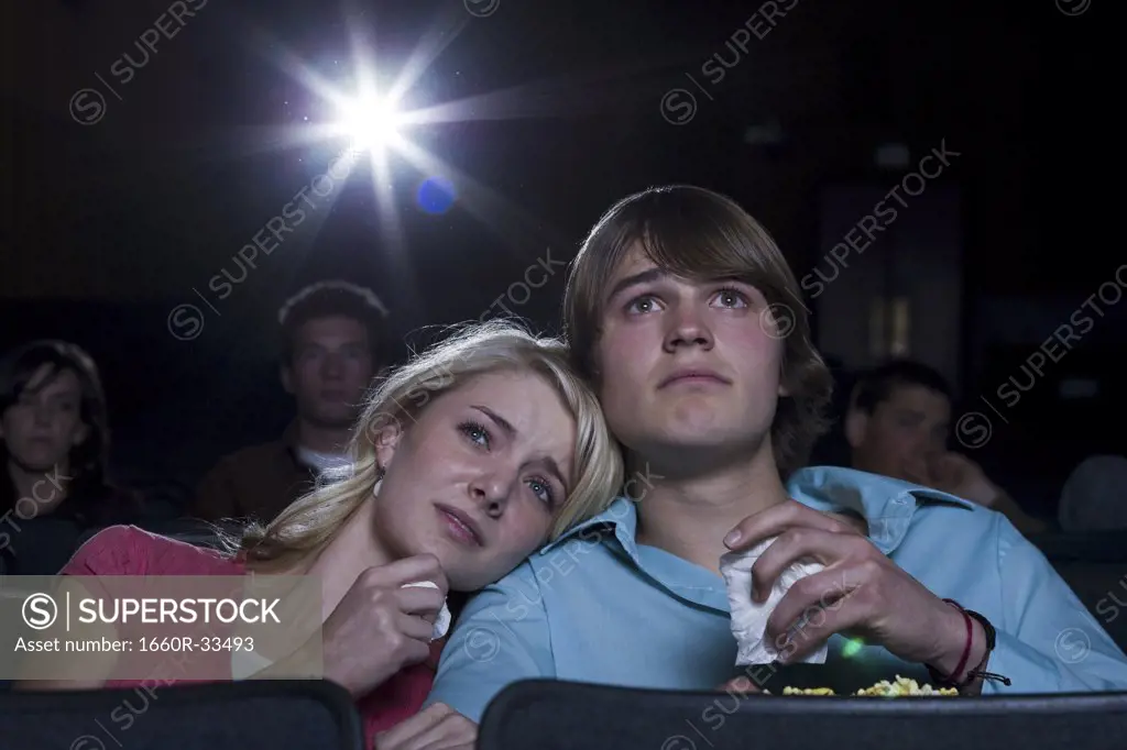 Boy and girl with tissues crying at movie theater
