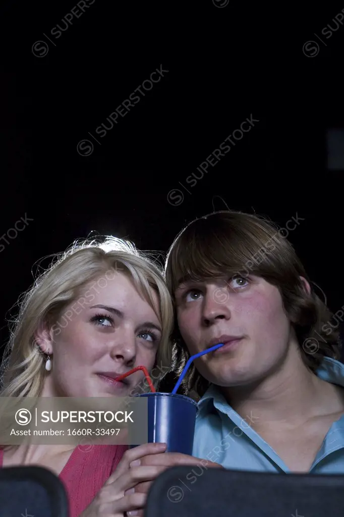 Boy and girl sharing beverage at movie theater