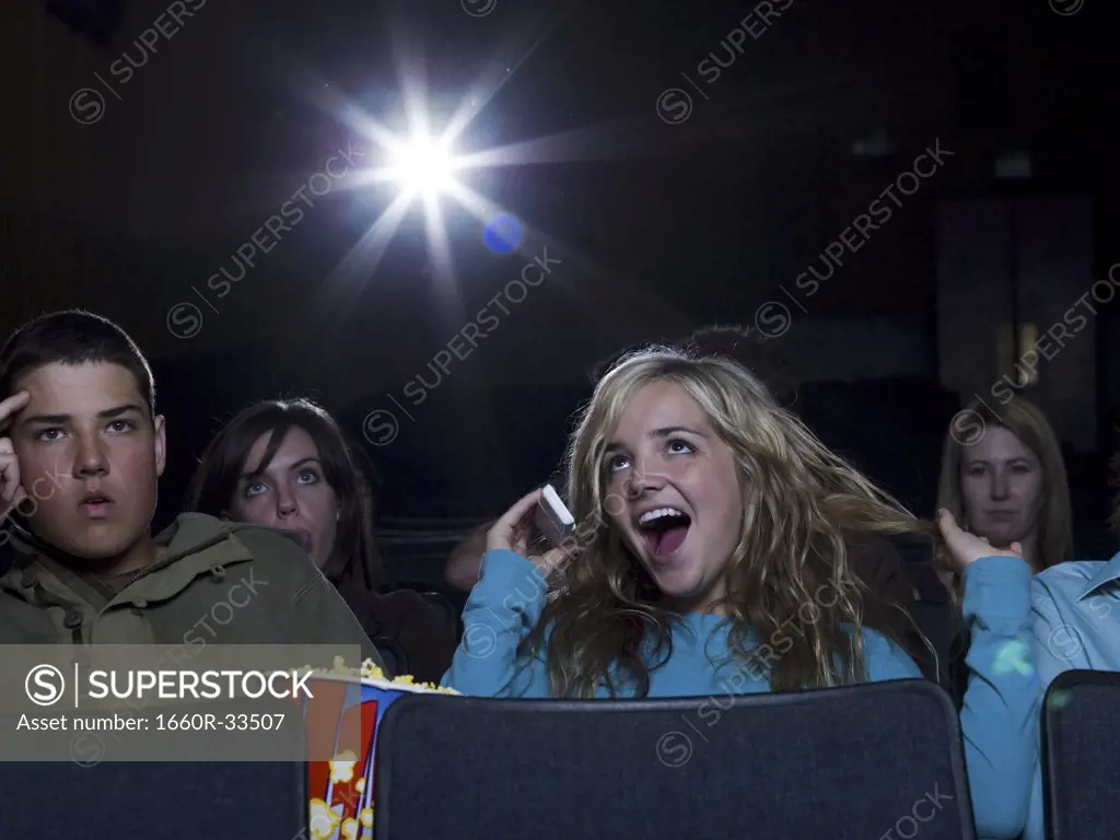 Girl talking on cell phone at movie theater with annoyed boy