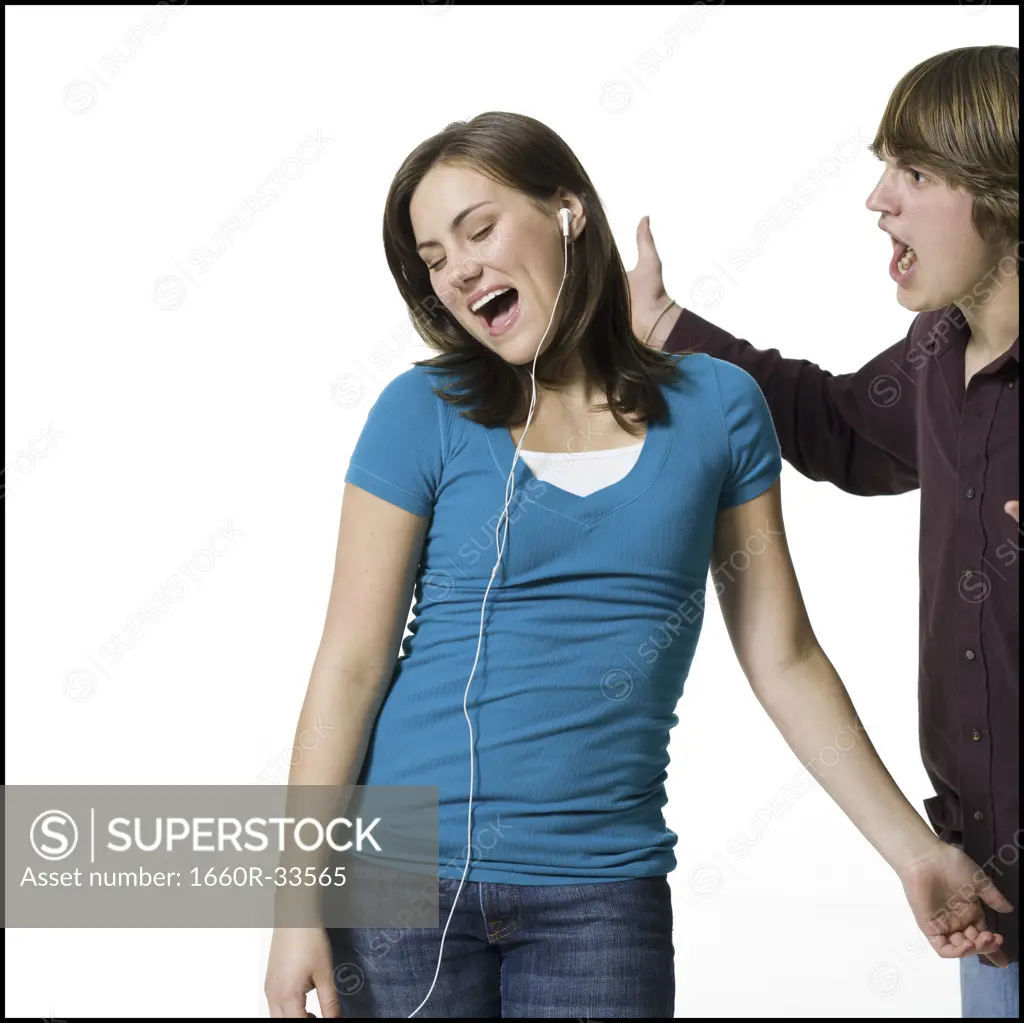Girl listening to mp3 player with boy yelling
