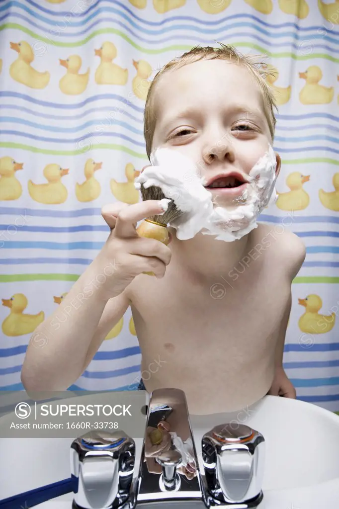 Boy shaving in bathroom and smiling