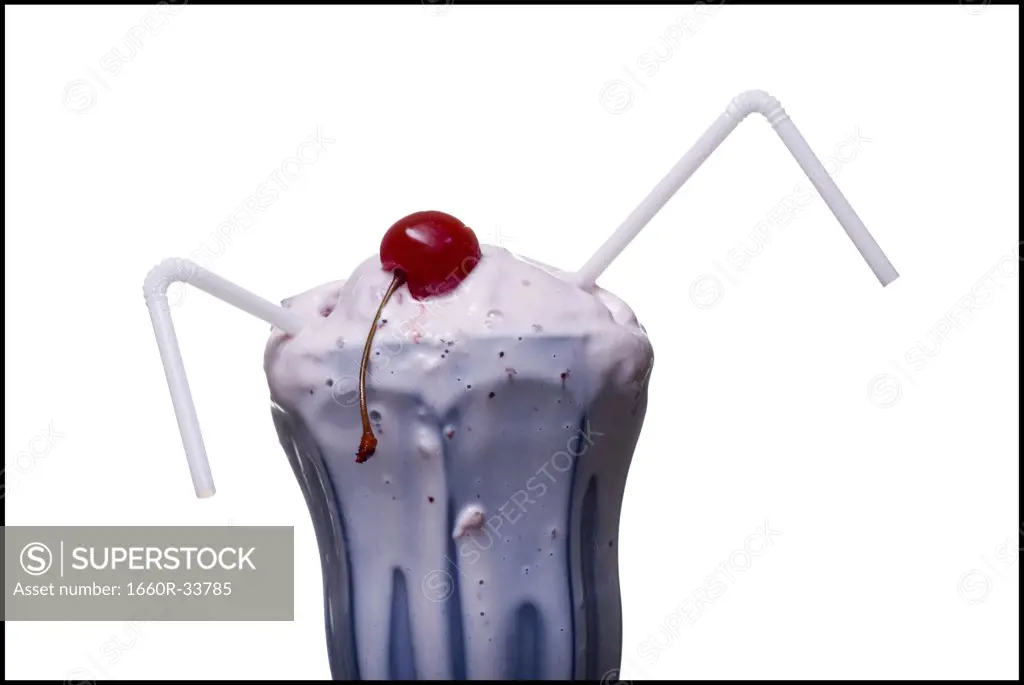 Melting milkshake with straw and cherry