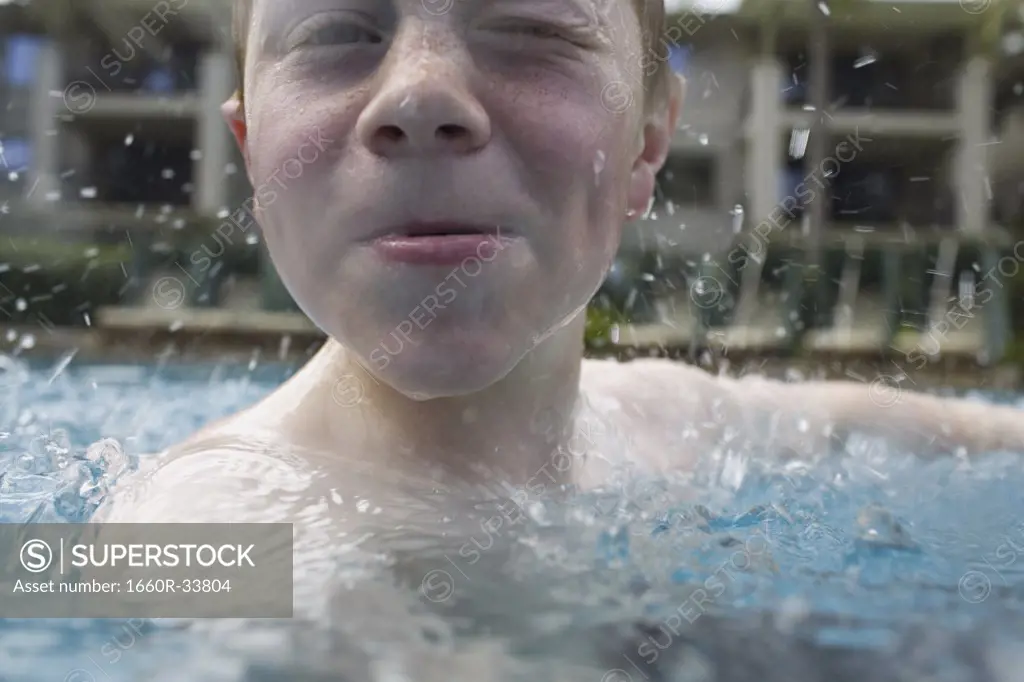 Boy in outdoor pool making funny face