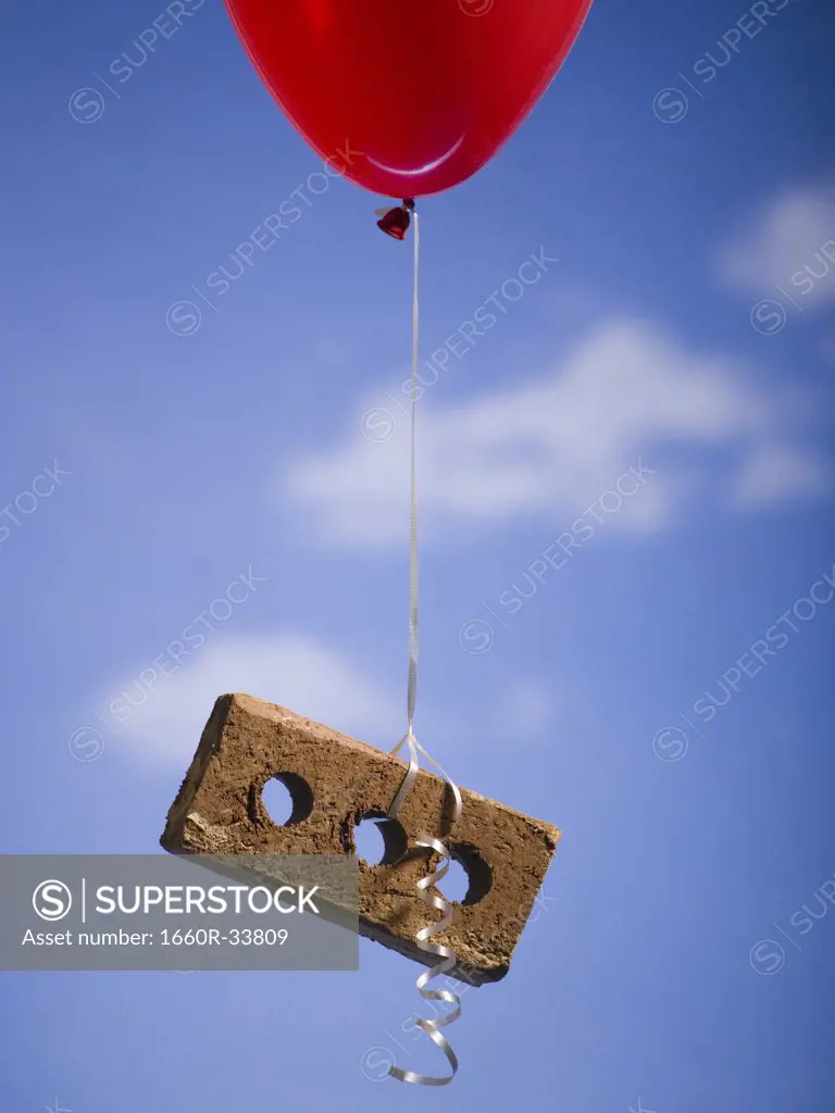 Helium balloon lifting brick outdoors