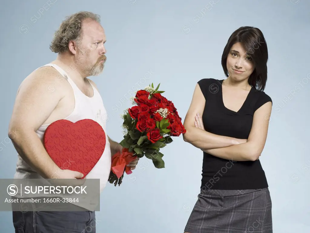 Disheveled man with heart box and red roses with disinterested woman