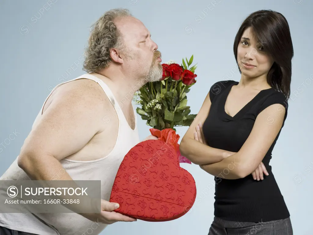 Disheveled man with heart box and red roses with disinterested woman