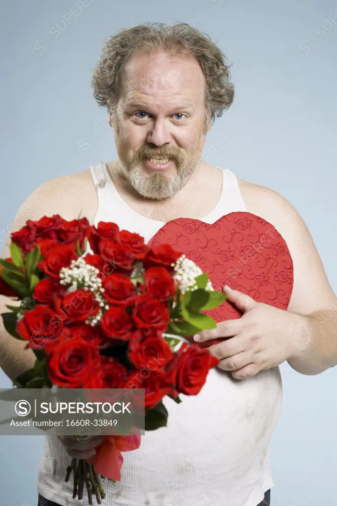 Disheveled man with red roses and heart box smiling