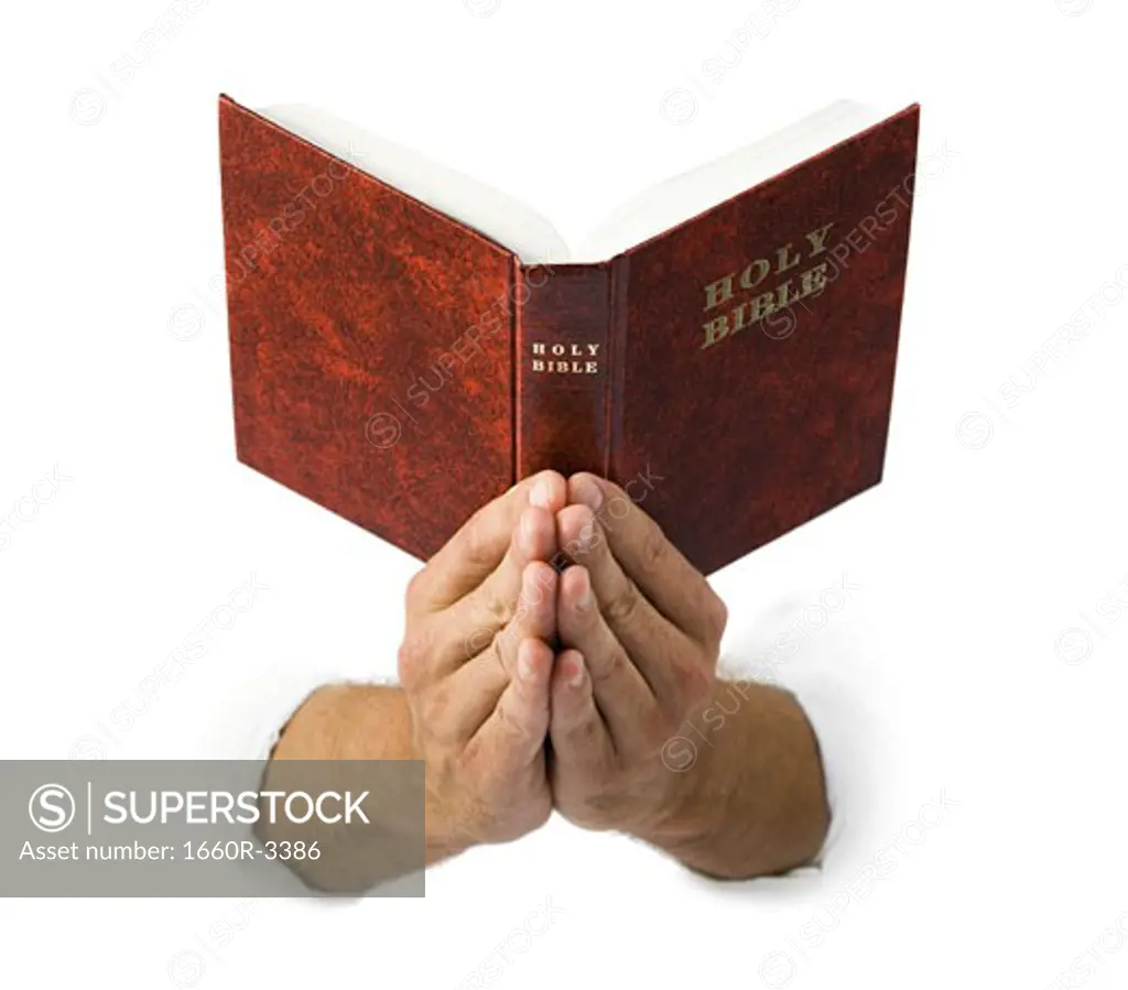 Close-up of praying hands holding the Bible