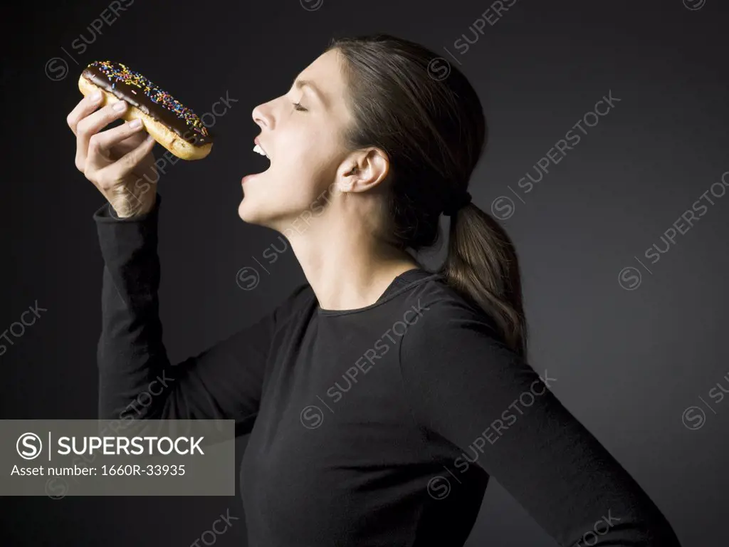 Profile of woman eating an ©clair donut