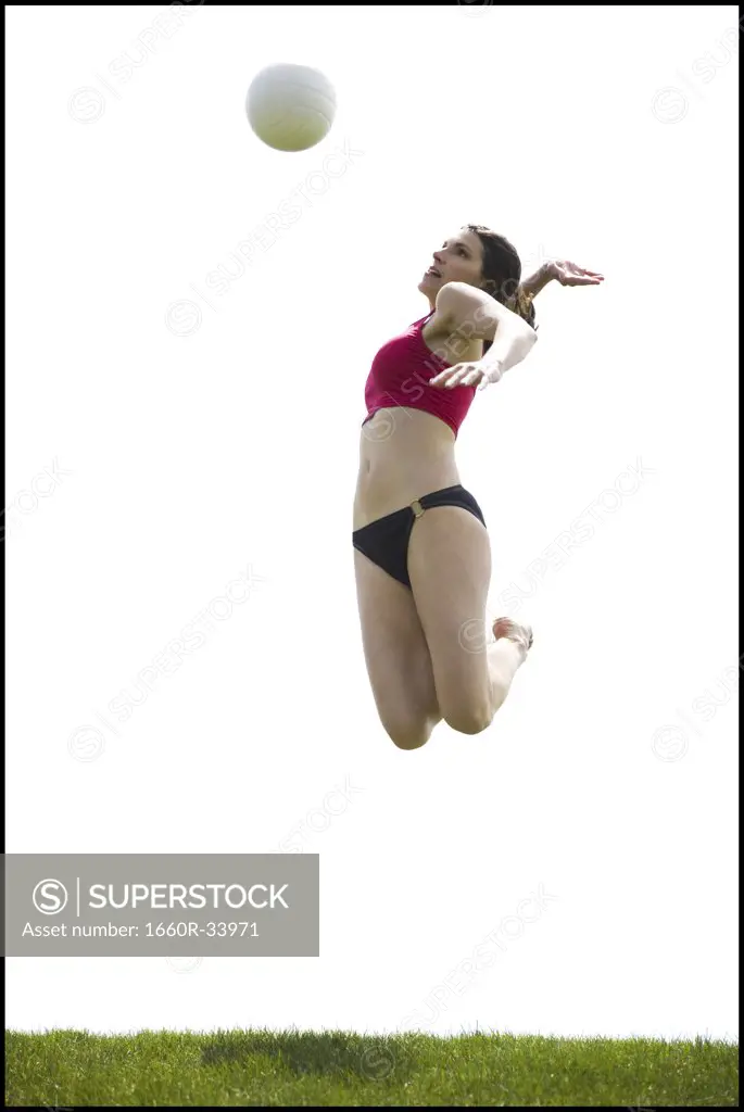 Woman jumping and spiking volleyball outdoors