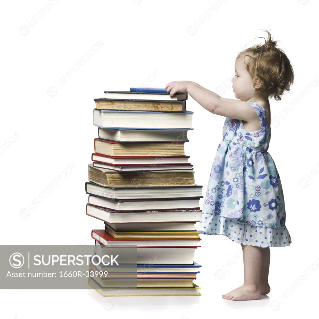 Young girl standing beside stack of hardcover books