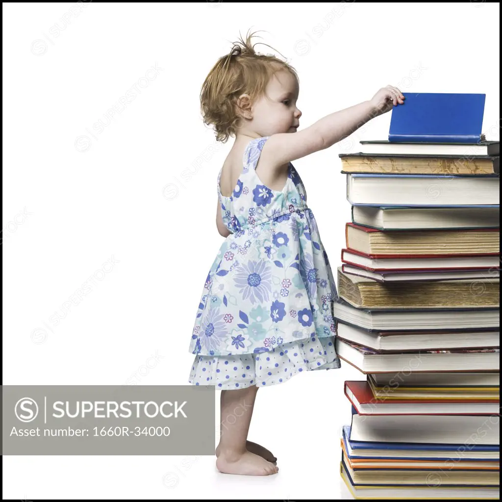 Young girl standing beside stack of hardcover books