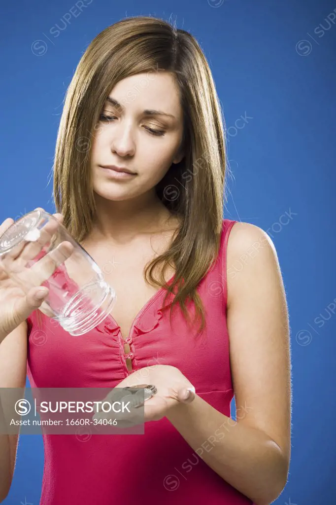 Woman emptying coins from jar into hand