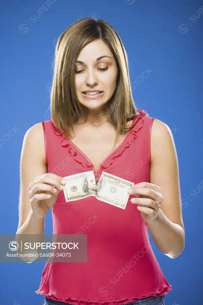 Woman tearing American hundred dollar bill