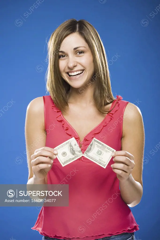Woman tearing American hundred dollar bill smiling