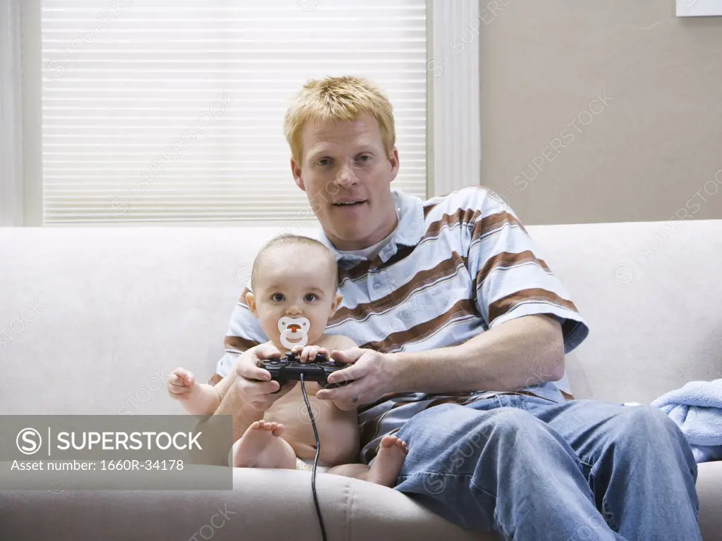 Man and baby on sofa with video game controller smiling