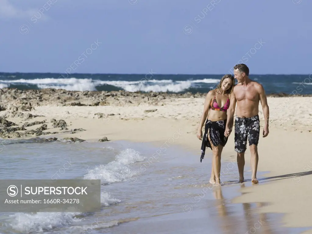 Man and woman walking on shoreline embracing