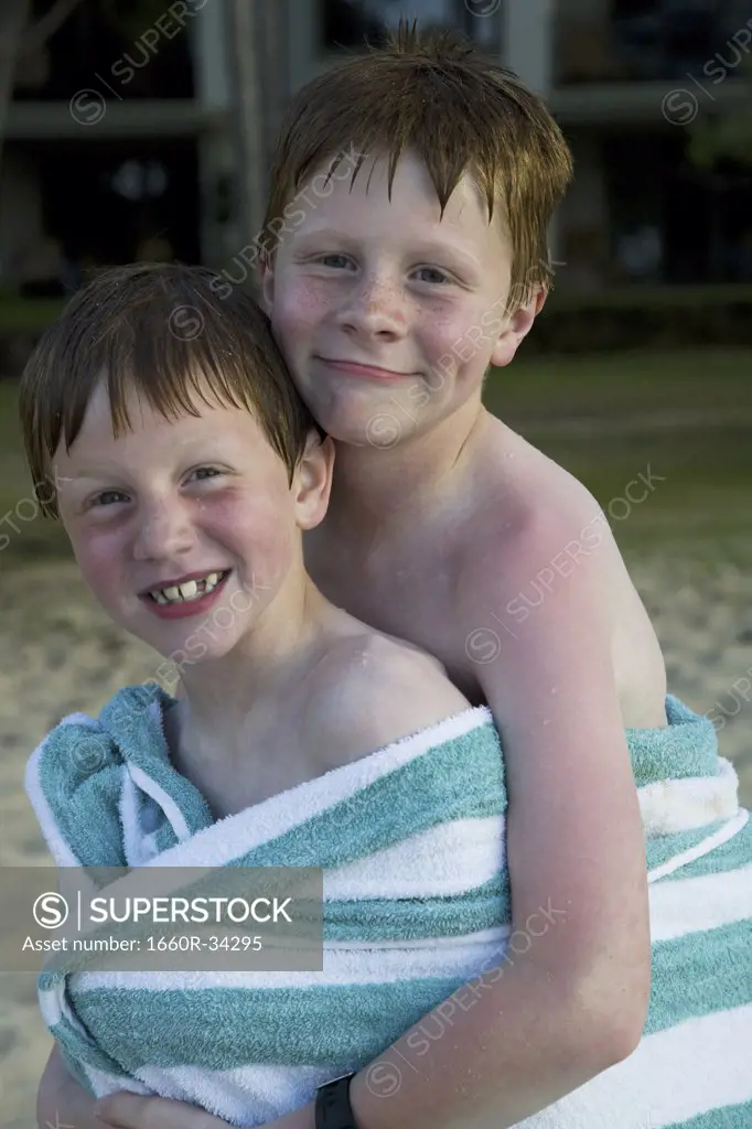Two boys wrapped in towel outdoors smiling