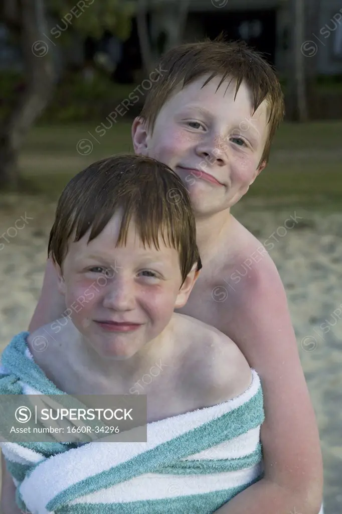 Two boys wrapped in towel outdoors smiling