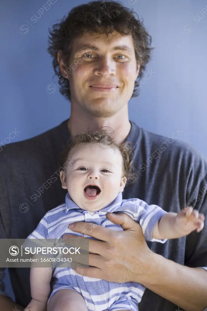 Man holding baby boy square to camera smiling