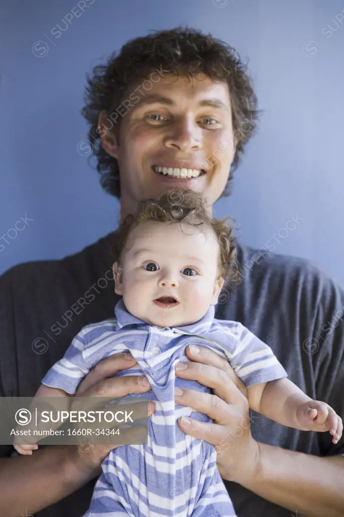 Man holding baby boy square to camera smiling