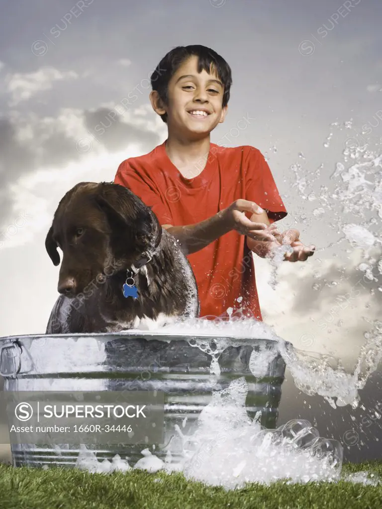 Boy bathing dog outdoors smiling