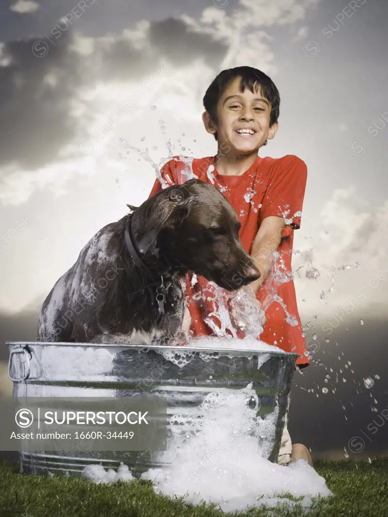 Boy bathing dog outdoors smiling