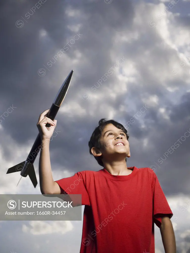 Boy playing with toy rocket outdoors on cloudy day low angle view