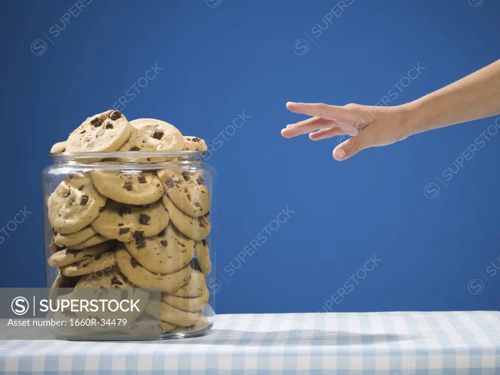 Hand reaching for chocolate chip cookie jar
