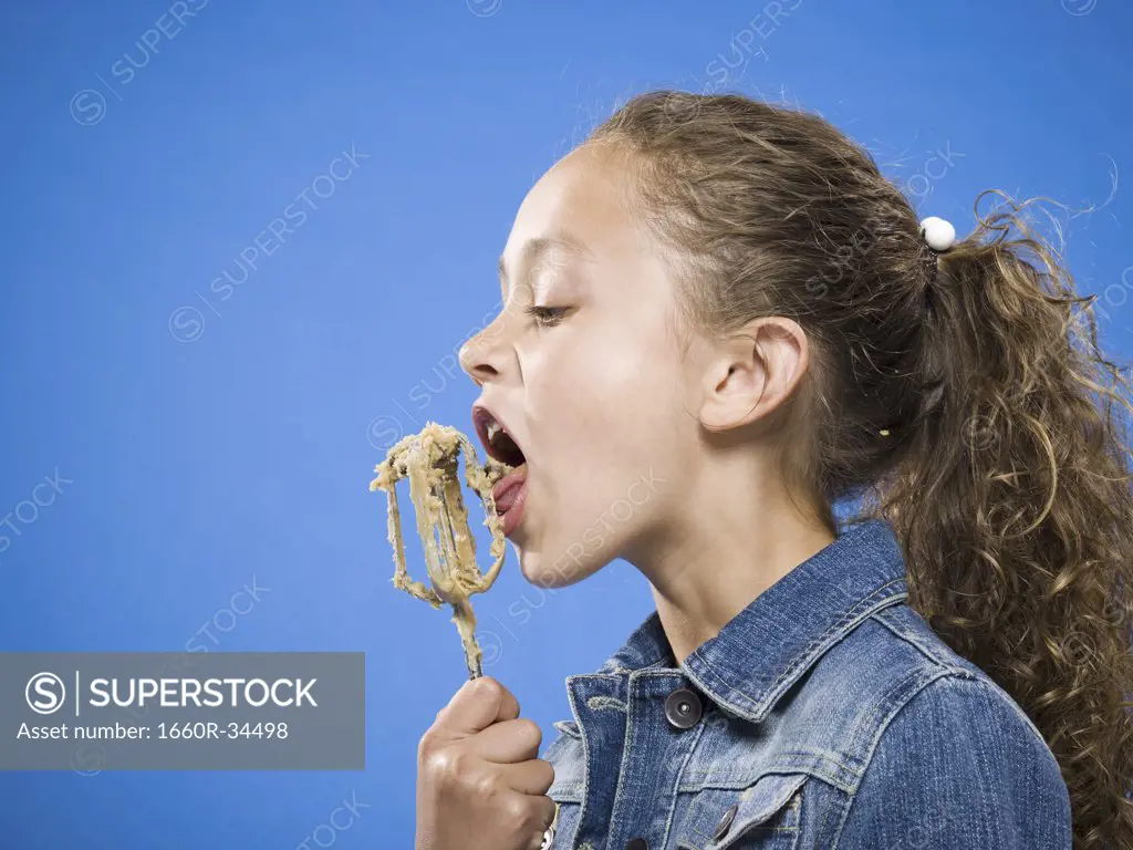 Profile of girl licking batter off beater