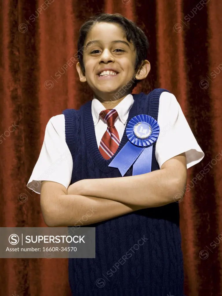 Boy with blue ribbon smiling with arms crossed