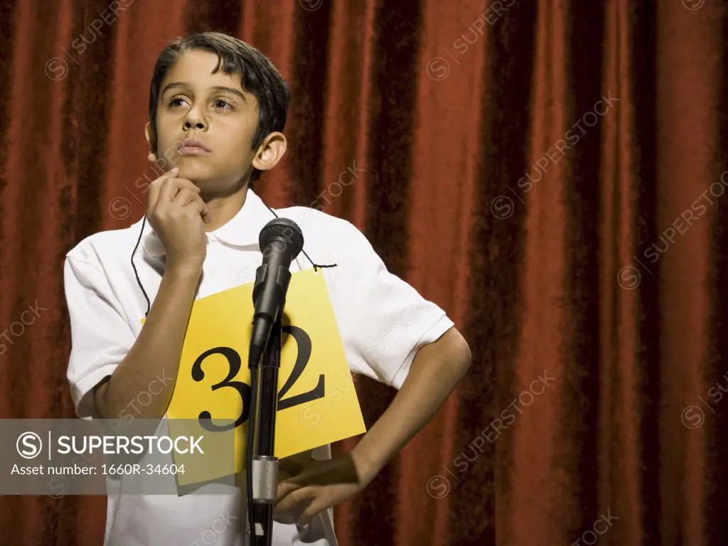 Boy contestant standing at microphone thinking